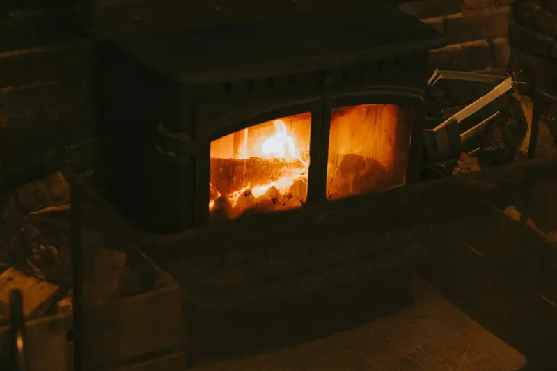 Mörk vardagsrumshörna med en kamin där elden lyser genom luckan